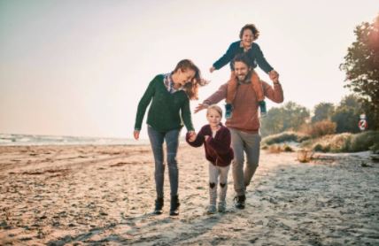 Famillle en train de sourire et de marcher sur la plage